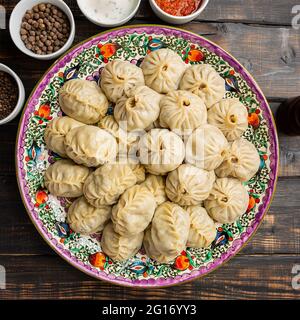 Usbekisch bereitete gekochte Manti- oder Mantelknödel in einer traditionellen Schüssel auf einem rustikalen Holztisch zu. Stockfoto