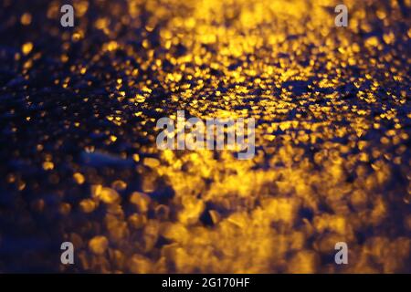 Abstraktes Bild von gelbem Licht, das von unebener schwarzer Oberfläche reflektiert wird Stockfoto