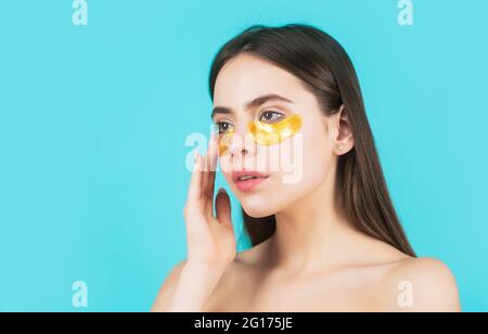 Frau, die goldene Augenflecken aufführt. Nahaufnahme Porträt Mädchen. Portrait der Beauty-Frau mit Augenflecken, die einen Effekt der perfekten Haut zeigen. Augenmaske Stockfoto