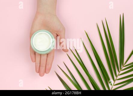 Ein offenes Glas mit Creme in der Hand einer Frau. Bio-Kosmetik für die Hautpflege. Schönheitskonzept Stockfoto