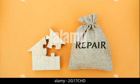 Geldbeutel mit dem Wort Repair und einem Holzhaus. Das Konzept eines beschädigten Hauses, baufällige Wohnungen. Hausreparatur nach einer Katastrophe. Renovierung, Renovierung Stockfoto