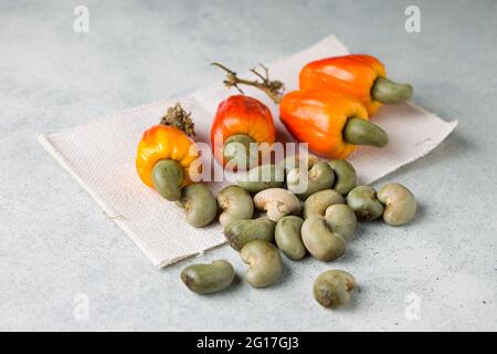 Cashew-Apfel und Cashew-Samen werden auf grauen strukturierten Hintergrund, Draufsicht platziert. Stockfoto