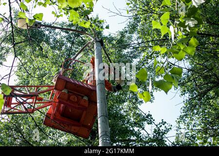 Dnepropetrovsk, Ukraine - 05.27.2021: Ein kommunaler Arbeiter in Schutzausrüstung führt gefährliche Arbeiten durch, um eine Unterbrechung der Stromversorgung gri zu beseitigen Stockfoto