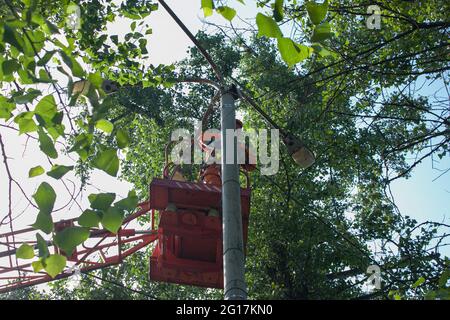 Dnepropetrovsk, Ukraine - 05.27.2021: Ein kommunaler Arbeiter in Schutzausrüstung führt gefährliche Arbeiten durch, um eine Unterbrechung der Stromversorgung gri zu beseitigen Stockfoto