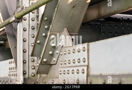 Schienenbrücke, Detail auf Stahlplatten, Gelenke, große Muttern und Schrauben von der Sonne beleuchtet. Abstrakter industrieller Hintergrund Stockfoto