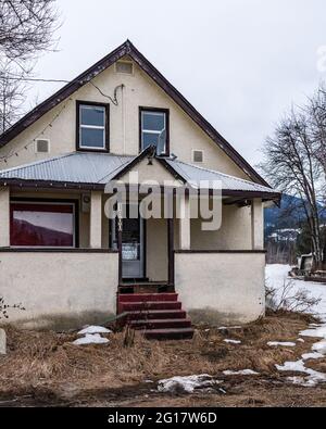 REVELSTOKE, KANADA - 14. MÄRZ 2021: Altes Haus in Kleinstadt Abendzeit früher Frühling mit Schnee. Stockfoto