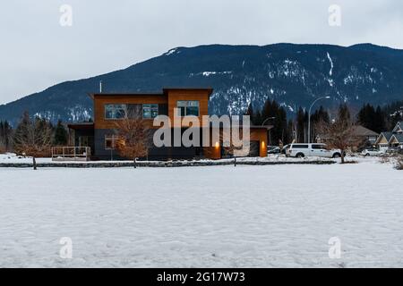 REVELSTOKE, KANADA - 14. MÄRZ 2021: Privathaus und Straßenansicht in Kleinstadt Abendzeit früher Frühling mit Schnee. Stockfoto
