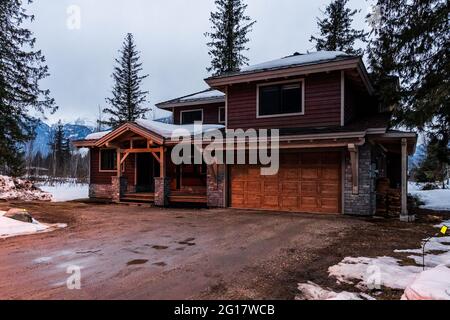 REVELSTOKE, KANADA - 14. MÄRZ 2021: Privathaus und Straßenansicht in Kleinstadt Abendzeit früher Frühling mit Schnee Stockfoto