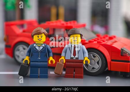 Tambow, Russische Föderation - 04. Juni 2021 Lego Geschäftsmann und Geschäftsfrau minifiguren stehen in der Nähe ihres Luxus-Sportwagen. Stockfoto