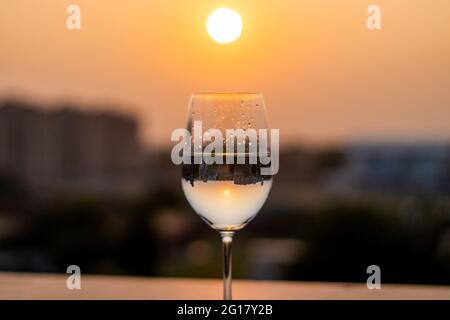 Bei Sonnenuntergang wird Flüssigkeit in ein Weinglas gegossen Stockfoto