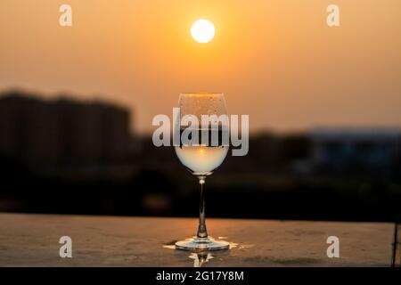 Bei Sonnenuntergang wird Flüssigkeit in ein Weinglas gegossen Stockfoto