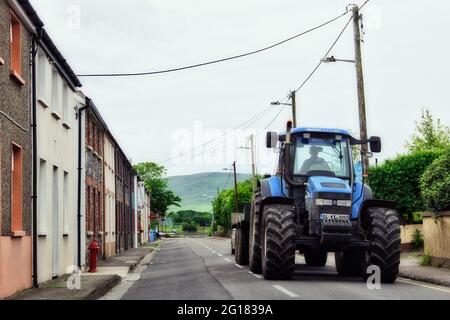 CORK, IRLAND - JUNI 6 2012: Ein blauer New Holland Traktor auf der Straße in der ländlichen Gegend von Dingle, Irland Stockfoto