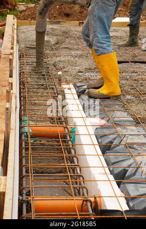 Bauherren gießen Beton auf die Fundamente eines kleinen Hauses. Die Fundamente bestehen aus Stahlverstärkungskäfigen und -Maschen sowie Radon iglus. Udine, IT Stockfoto