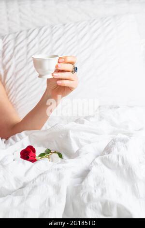 Kaffee im Bett: Frauen halten eine Kaffeetasse in der Hand Stockfoto