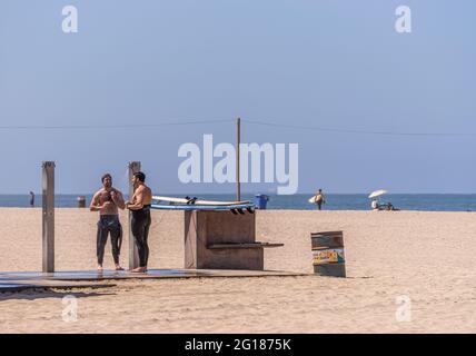 Santa Monica, CA, USA - 20. Juni 2013: Nahaufnahme von ein paar männlichen Surfern, die am Sandstrand unter blauem Himmel duschen. Stockfoto