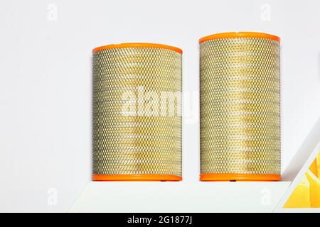 Große zylindrische Autoluftfilter, umrahmt mit Metallgeflecht auf hellem Hintergrund. Nahaufnahme, Kopierbereich. Stockfoto