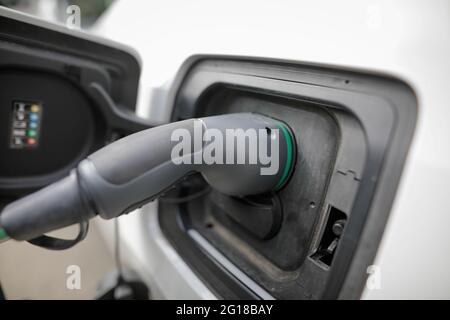 Bild mit geringer Schärfentiefe (selektiver Fokus) mit einem Ladekabel für Elektroautos und Stecker an einer Ladestation. Stockfoto