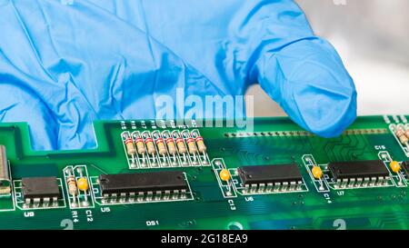 Elektronische Bauteile auf grüner Leiterplatte auf menschlicher Hand. Nahaufnahme von schwarzen IC-Chips, Kondensatoren oder Widerständen auf der Leiterplatte der Computertastatur. Stockfoto