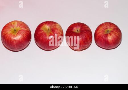 Hochwinklige Aufnahme reifer roter Äpfel in einer Reihe auf einer weißen Oberfläche Stockfoto