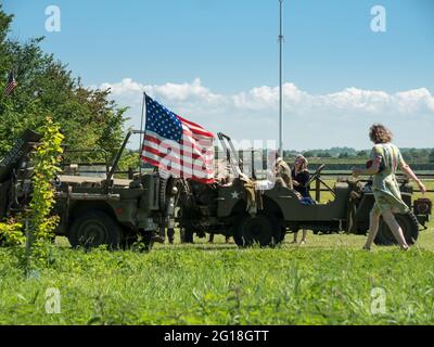 NORMANDIE, Colleville-Montgomery, FRANKREICH Juni 2021: Rekonstruktion einer alliierten Tageslandung in der Normandie, Autos, Lastwagen, Menschen in Uniform. Feiern Stockfoto