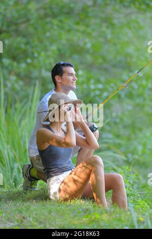 Das Paar saß auf der Grasbank und fischt Stockfoto