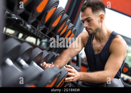 Mann, der in einem Fitnessstudio Gewicht wählt Stockfoto