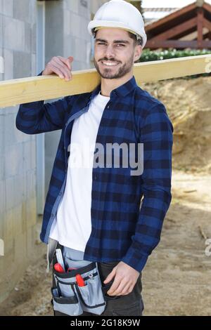 Mann im Helm trägt Holz Stockfoto