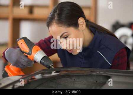 auto Mechaniker Frau mit elektrischem Schraubendreher Stockfoto