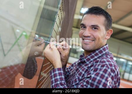 Glücklicher Elektriker, der die elektrische Wand mit Schraubendreher montiert Stockfoto