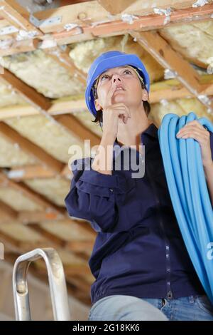 Eine Klempnerin, die an der Decke arbeitet Stockfoto