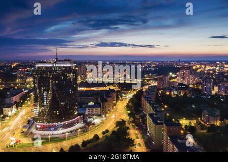 Panoramablick auf die Stadt Minsk bei Sonnenuntergang. Luftbild mit beleuchteten Gebäuden und Straßen. Stockfoto