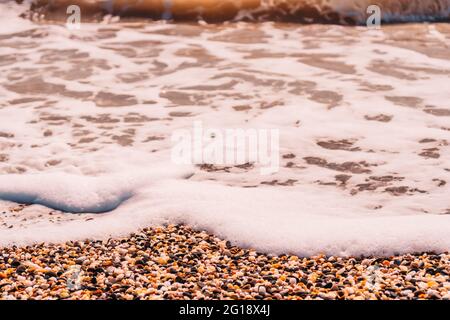 Abstrakte Natur Sommer oder Frühling Meer Meer Hintergrund. Kleine Wellen auf der goldenen, warmen Wasseroberfläche verwischen sich in Bewegung mit Bokeh-Lichtern vom Sonnenuntergang. Urlaub Stockfoto