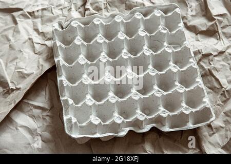 Nahaufnahme des leeren Eierfachs auf dem Hintergrund des zerknitterten Papiers. Das Konzept von Recycling, Wiederverwendung. Stockfoto