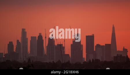 Wimbledon, London, Großbritannien. 6. Juni 2021. Wolkenkratzer im Zentrum von London wurden vor einem orangefarbenen Morgenhimmel silhouettiert. Quelle: Malcolm Park/Alamy Live News Stockfoto