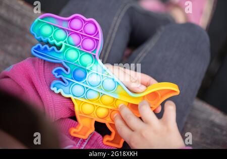 Beliebte bunte Anti-Stress-Touch-Spielzeug Fidget Push Pop es in die Hände eines Kindes. Stockfoto