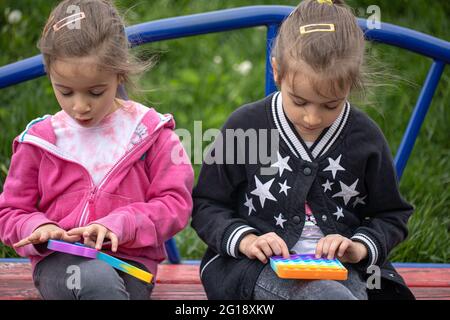Kinder spielen mit einem beliebten Spielzeug Pop it, halten in den Händen Anti-Stress, Silikon-Spiel. Stockfoto