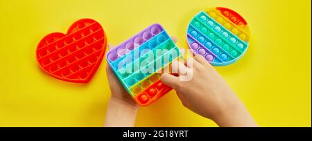 Kind Hände spielen mit bunten Pop Es fidget Spielzeug. Bunte Antistress Sinnesspielzeug Fidget Push Pop it. Stockfoto