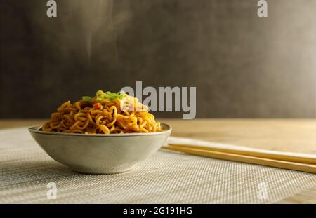 Japanisches Essen, Gemüsenudeln in Teriyaki-Sauce in einer Schüssel mit Essstäbchen auf der Seite serviert. Stockfoto