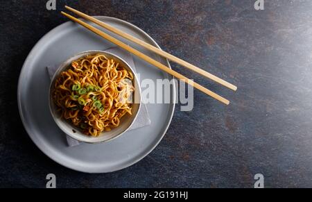 Japanisches Essen, Gemüsenudeln in Teriyaki-Sauce in einer Schüssel mit Essstäbchen auf der Seite serviert. Stockfoto