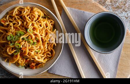 Japanisches Essen, Gemüsenudeln in Teriyaki-Sauce in einer Schüssel mit Essstäbchen auf der Seite serviert. Stockfoto