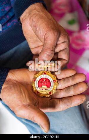 (210606) -- YICHUN, 6. Juni 2021 (Xinhua) -- Zhang Yingshan zeigt die Medaille des Nationalen Musterarbeiters, den er zu Hause in einer vom Wumahe-Forstbüro verwalteten Waldfarm in der Stadt Yichun, nordöstlich der Provinz Heilongjiang, im Nordosten Chinas, verliehen wurde, 3. Juni 2021. Zhang Yingshan, 65, arbeitet seit über 45 Jahren mit Bäumen. Nach dem Schritt seines Vaters wurde Zhang 1975 Forstarbeiter im Wumahe Forstamt. Neun Jahre später eröffnete er die erste familiengeführte Waldfarm des Büros, in der jedes Jahr 30 Hektar Bäume gepflanzt wurden. Von 1981 bis 2011, Zhang und seine Frau Yan Yupi Stockfoto