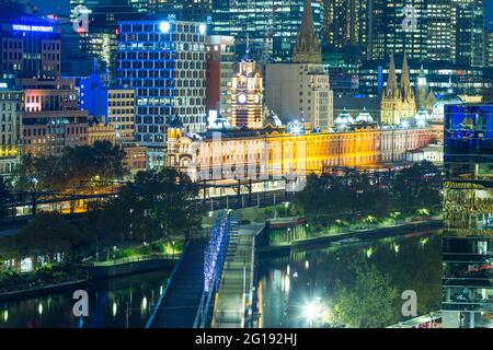 Flinders Street Station in Melbourne, Australien, bei Nacht gesehen, mit Blick auf die Sandridge Bridge, die den Yarra River überquert. Stockfoto