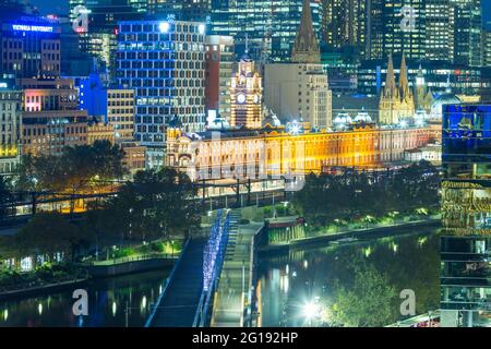 Flinders Street Station in Melbourne, Australien, bei Nacht gesehen, mit Blick auf die Sandridge Bridge, die den Yarra River überquert. Stockfoto