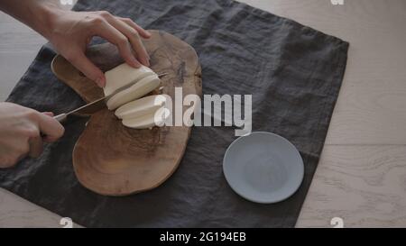 Mann schneiden Mozzarella auf Olivenholz-Brett für Sandwich, breites Foto Stockfoto