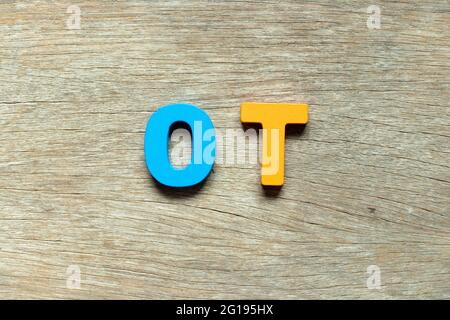 Farbe Alphabet Buchstaben in Wort OT (Abkürzung für Überstunden) auf Holz Hintergrund Stockfoto