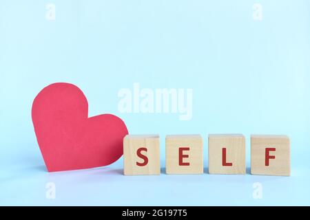 Selbstliebe und Pflege Konzept. Holzblöcke Typografie mit großen roten Herz Form Ausschnitt. Stockfoto