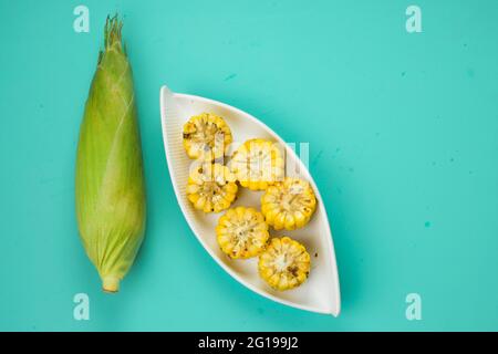 Mais, ein Snack aus reifem Mais und garniert mit Chilischoten und Honig in einem weißen schönen Geschirr, das auf einem festen Eis platziert ist angeordnet Stockfoto