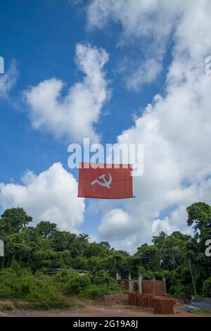 kommunistische Flagge. Hammer und Sichel, die die Bauern und die Arbeiter darstellen, fliegen im dichten, wolkigen blauen Himmel. Stockfoto