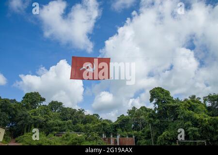 kommunistische Flagge. Hammer und Sichel, die die Bauern und die Arbeiter darstellen, fliegen im dichten, wolkigen blauen Himmel. Stockfoto