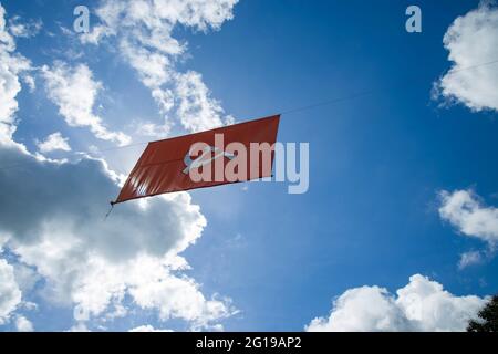 kommunistische Flagge. Hammer und Sichel, die die Bauern und die Arbeiter darstellen, fliegen im dichten, wolkigen blauen Himmel. Stockfoto
